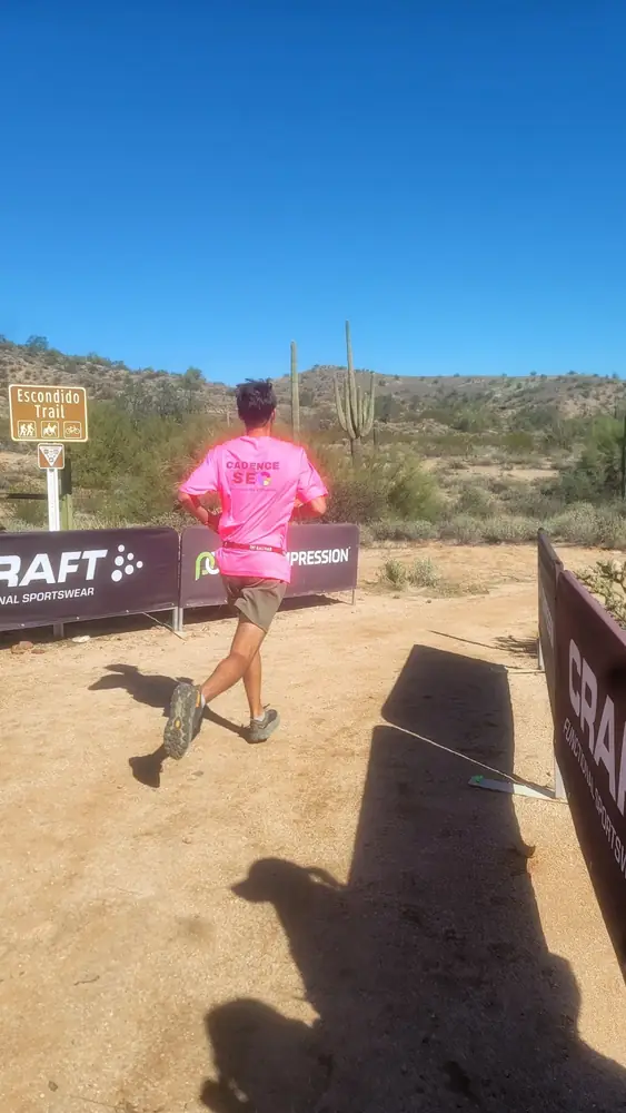 Runner wearing a pink Cadence SEO shirt on a desert trail